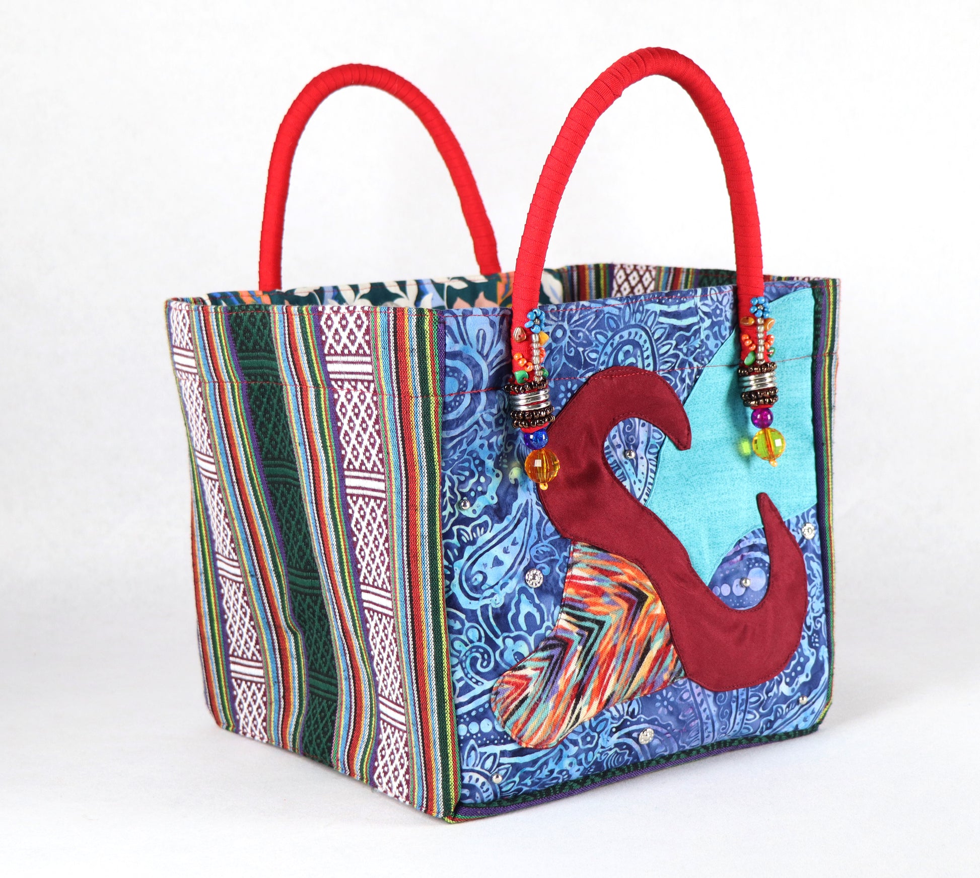 The bag comes in red handle, green Aztec pattern on the side, and a green, yellow, and blue flower pattern on the back.