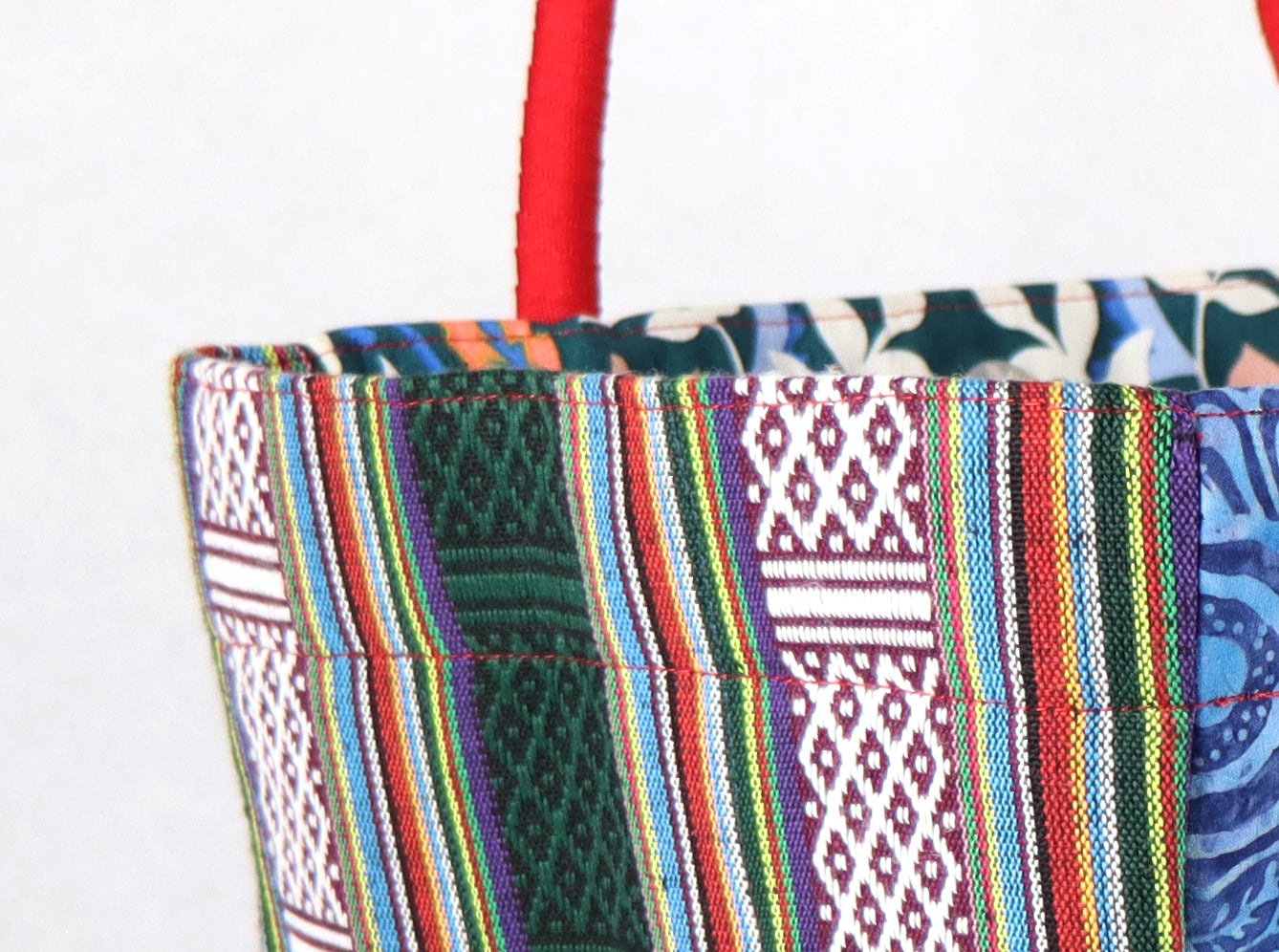 The bag comes in red handle, green Aztec pattern on the side, and a green, yellow, and blue flower pattern on the back.