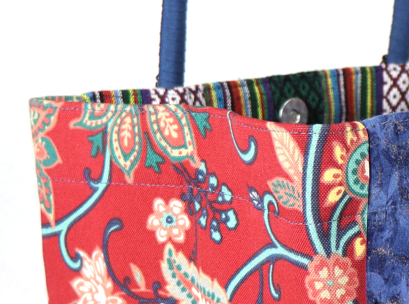 The bag comes in blue handle, red flower patterns on the side, and a green Aztec pattern on the back.